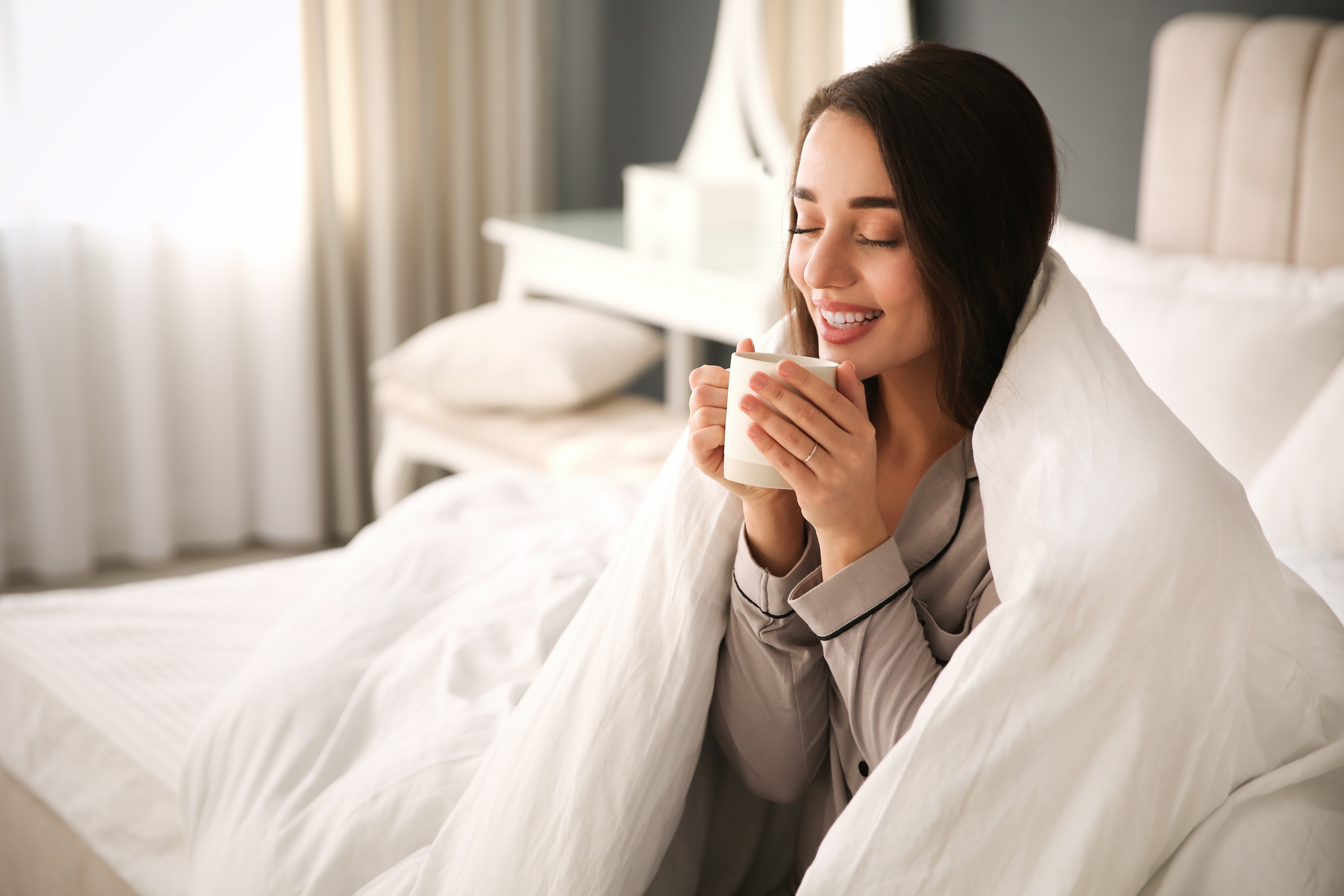 Woman enjoying cozy morning wrapped in fresh clean comforter